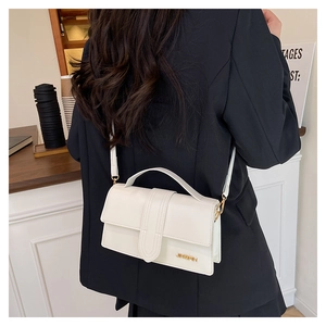 Sac à main rétro blanc en simili cuir avec logo métallique porté en sac bandoulière chic