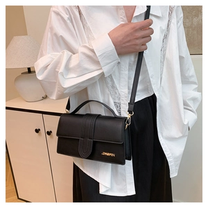 Détail d'un sac bandoulière en cuir noir avec garniture dorée et bandoulière