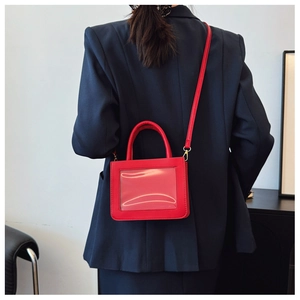 Detail of red crossbody bag with transparent window worn on dark navy oversized blazer