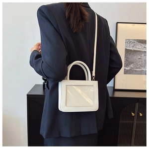 Petit sac blanc minimaliste à fenêtre transparente porté par un mannequin en extérieur