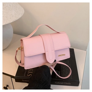 Detail of pink crossbody bag with gold metal logo and smooth leather texture