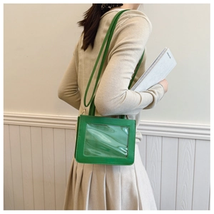 Side view of a grass green small square bag with clear window worn by a model