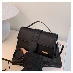 Détail d'un sac bandoulière noir minimaliste avec logo métallique JINGPIN doré et sangle