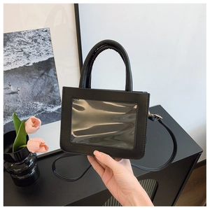 Close-up of black crossbody bag with clear PVC window and adjustable strap detail