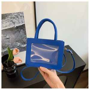 Detail of small blue PU leather tote bag with transparent window and gold metal hooks