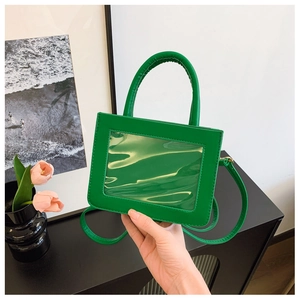 Detail of lime green mini bag with transparent window and top handle held by hand
