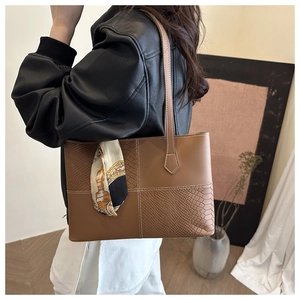 Detail of vintage brown tote bag featuring snakeskin texture contrast and decorative silk scarf