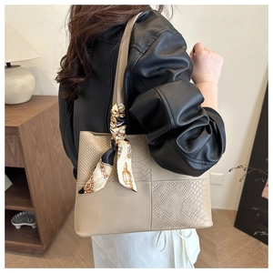 Detail of beige tote bag with animal texture and elegant silk scarf on handle