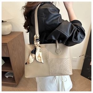 Detalle de un bolso tote beige con costuras geométricas, textura de serpiente y pañuelo