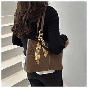 Detail of brown tote bag with snake-embossed texture and decorative silk scarf