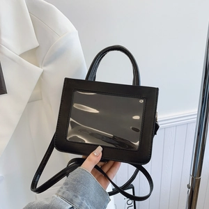 Minimalist black crossbody handbag with transparent window and top handle shown in hand