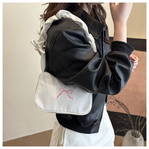 Détail du sac blanc sous le bras avec broderie nœud rose et poignée à volants