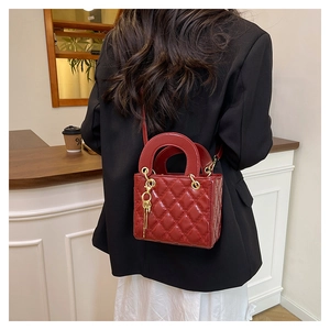 Detail of red quilted patent leather handbag with gold hardware and tassel charm