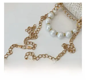 Detail of luxury pearl chain handle with gold metal links and rhinestone accents