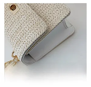 Detail showing cross-weave texture and golden metal rotary lock on cream straw bag