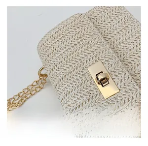 Detail of beige woven straw handbag featuring golden rectangle twist lock and metal chain