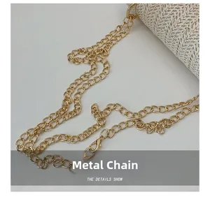 Detailed macro view of the golden hardware chain strap on a woven straw handbag