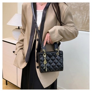 Close-up of black quilted leather handbag with gold hardware and key-shaped charm