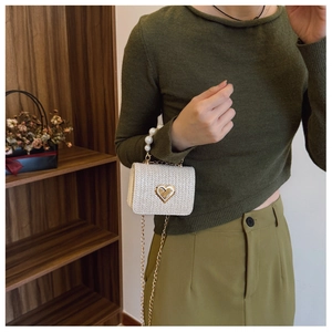 Detail of woven straw bag with golden heart lock and elegant faux pearl handle