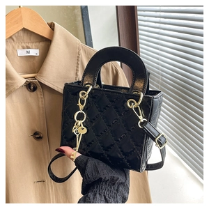 Detail of black quilted mini bag with gold chain charm and faux leather texture