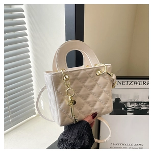 Detailed shot of quilted pattern texture on cream crossbody bag with gold key charm