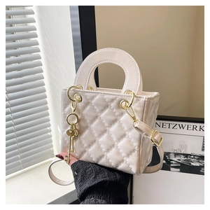 Detail of white quilted crossbody bag with golden hardware and a key-shaped pendant