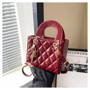 Macro view of red quilted patent leather handbag with gold hardware and charm
