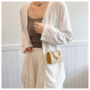 Detailed view of woven straw mini bag with pearl handle and golden chain strap