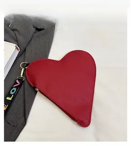 Detail of red heart-shaped clutch bag with lychee grain leather and LOVE woven strap
