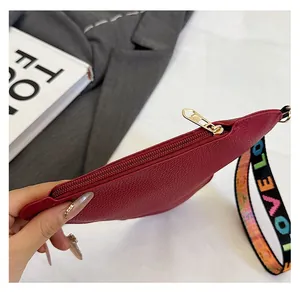 Detail of burgundy lychee grain leather purse with golden zipper and LOVE wristlet