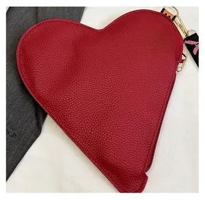Detail shot of heart-shaped red leather purse with zipper and wavy patterned lanyard