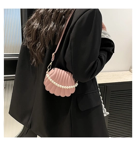 Detail of pink shell-shaped crossbody bag with decorative pearl chain and shoulder strap