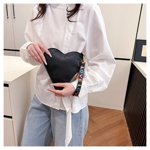 Détail du sac à main cœur noir en cuir grainé avec dragonne colorée arborant le mot LOVE