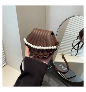 Détail du sac bandoulière marron en forme de coquillage avec perles et matelassage
