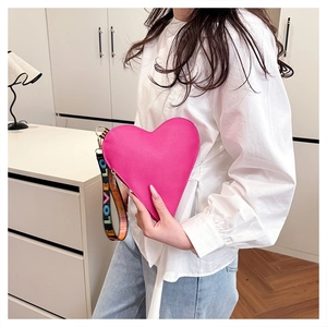 Detail of rose red heart-shaped leather clutch with LOVE embroidered fabric strap