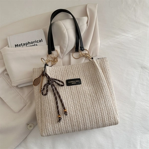 Off-white woven straw tote bag with black leather handles and tennis racket charm
