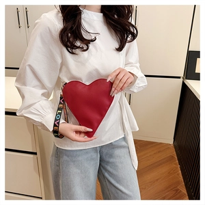 Detail of red heart-shaped leather clutch with colorful LOVE printed wrist strap