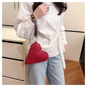 Detail of red heart-shaped clutch with embroidered LOVE wristlet strap and leather texture