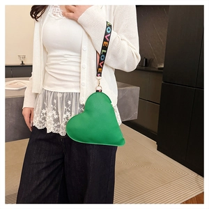 Detail of green heart-shaped crossbody bag with a LOVE patterned woven strap