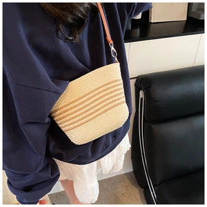 Detail of hand-woven straw crossbody bag featuring stripe texture and leather strap