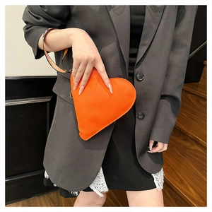 Orange heart-shaped wristlet clutch bag with lychee grain and geometric strap detail