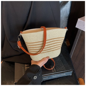 Close-up of striped straw bucket bag with orange leather strap and metal clasp detail
