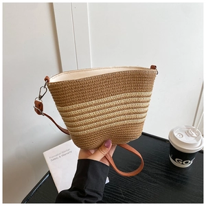 Detailed shot of woven straw bucket bag texture with leather strap and silver metal hook