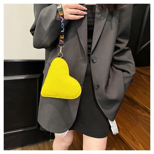 Detail of yellow heart-shaped leather bag with colorful LOVE embroidered wide strap