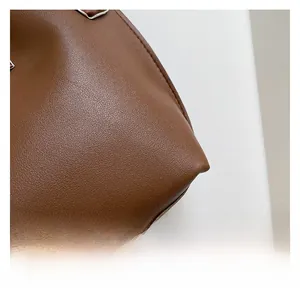 Detailed close-up showing brown pebble grain leather texture and quality stitching on bag