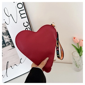 Détail de la pochette rouge en forme de cœur avec cuir litchi et dragonne LOVE