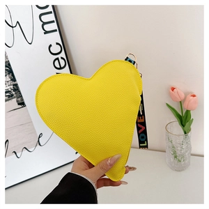 Détail du porte-monnaie cœur en cuir jaune avec dragonne brodée Love en main