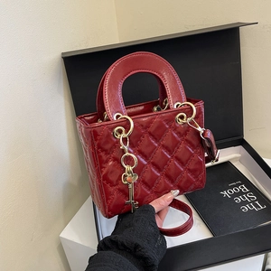 Glossy red quilted patent leather handbag with gold key charm in luxury setting