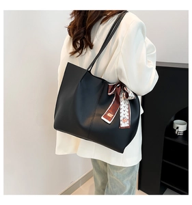 Detail of a large black leather tote bag with decorative silk scarf on the side