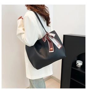 Detail of black faux leather tote bag with red and white silk scarf on shoulder